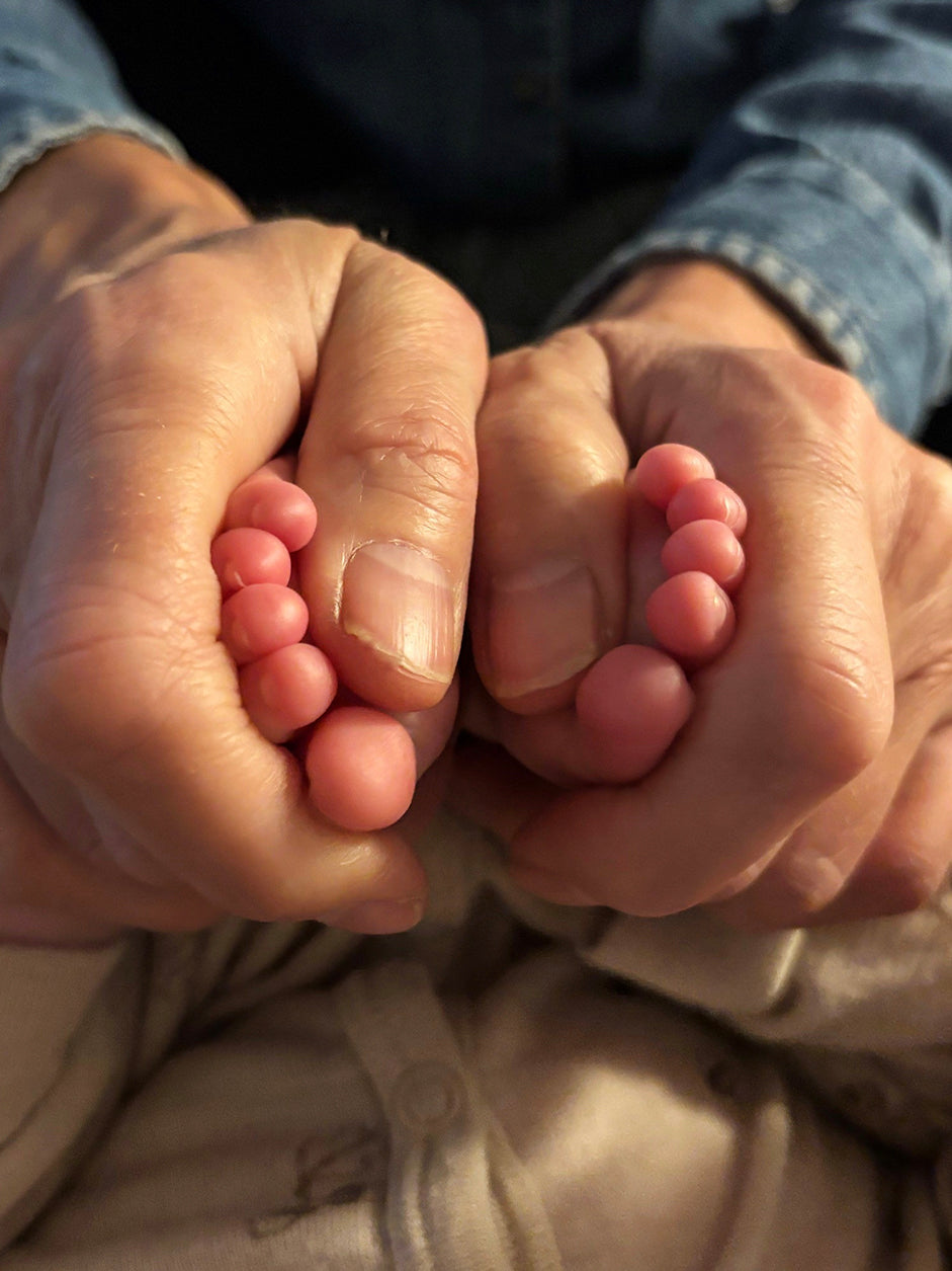 Babyfødder holdt i hænder tæt på kameraet.