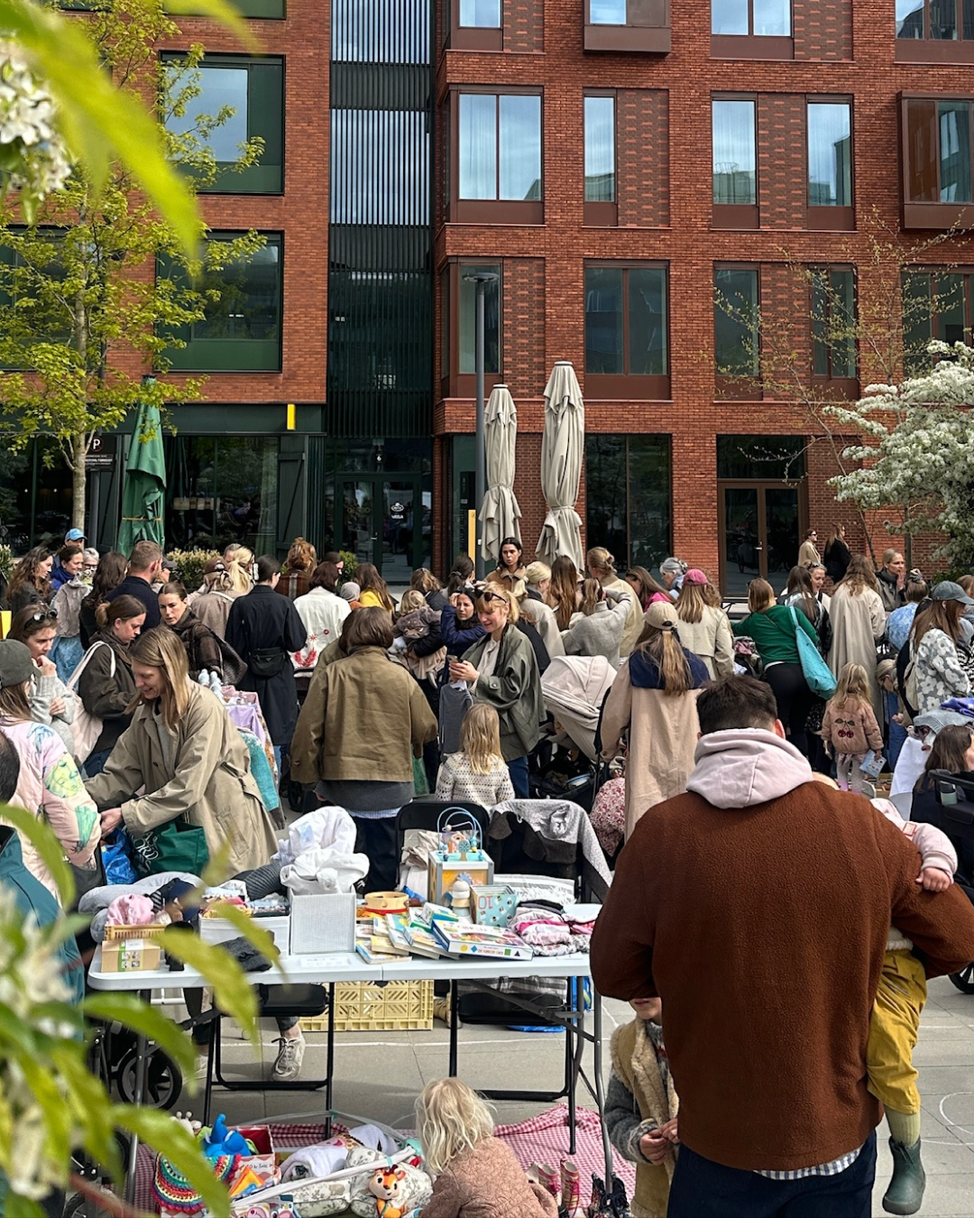Udendørs børneloppemarked på Kildepladsen med familier, børn og boder foran Bette Café.